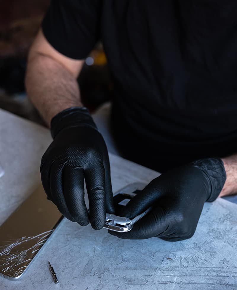 Manos con guantes negros trabajan sobre un celular abierto